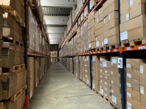 A long corridor in a warehouse with orange shelves stacked with labelled boxes.