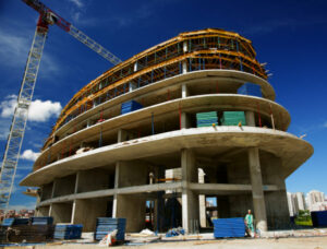 Construction site of a big building with a crane and insulation material piled in front.