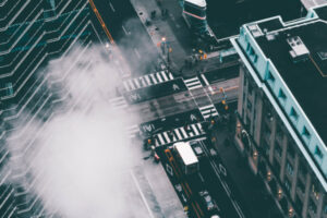 Drone view of streets with skyscrappers and smoke rising up.